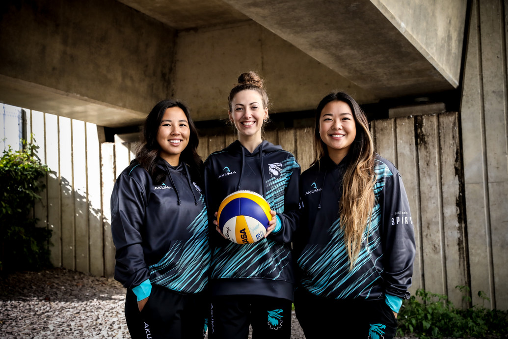 Three athletes standing with a ball