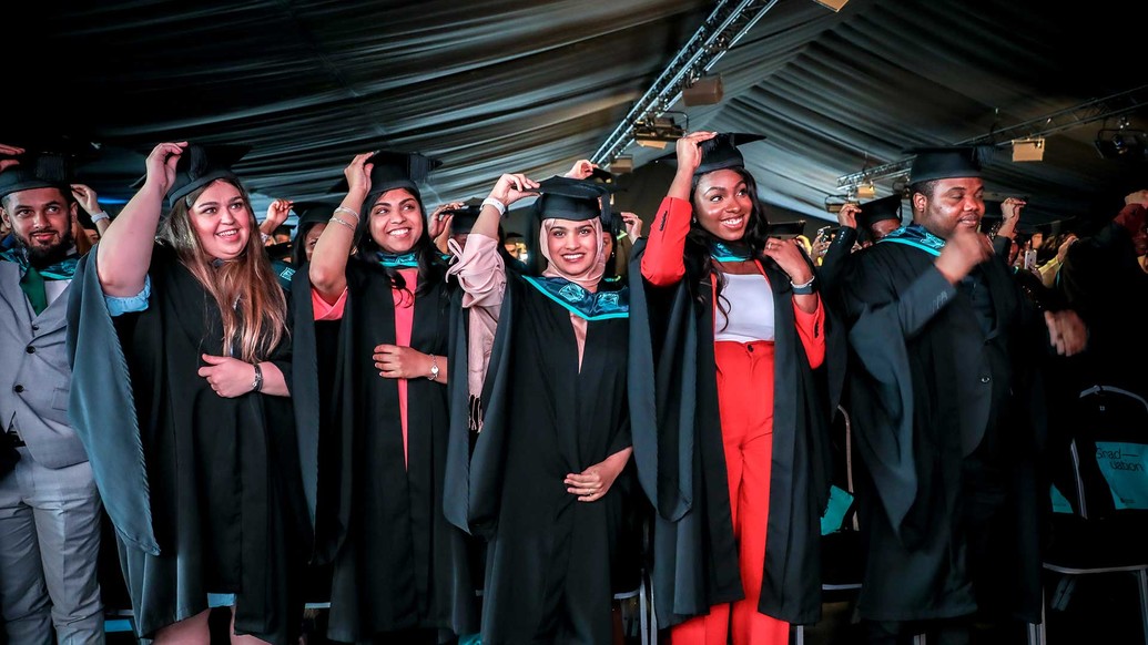 Students tipping hats in graduation 2021
