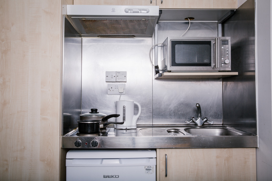 A kitchenette showing Kettle, sink, microwave and cooker top.