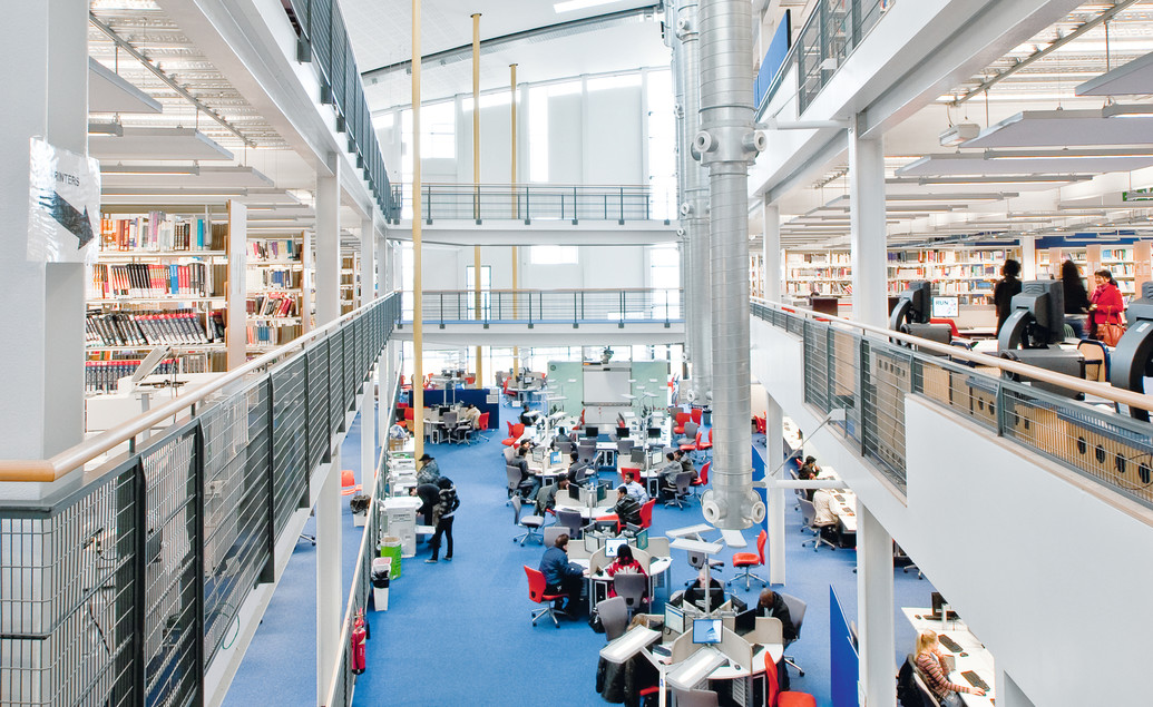 A wide-angle shot of students sitting at various tables in the Docklands Campus Library.