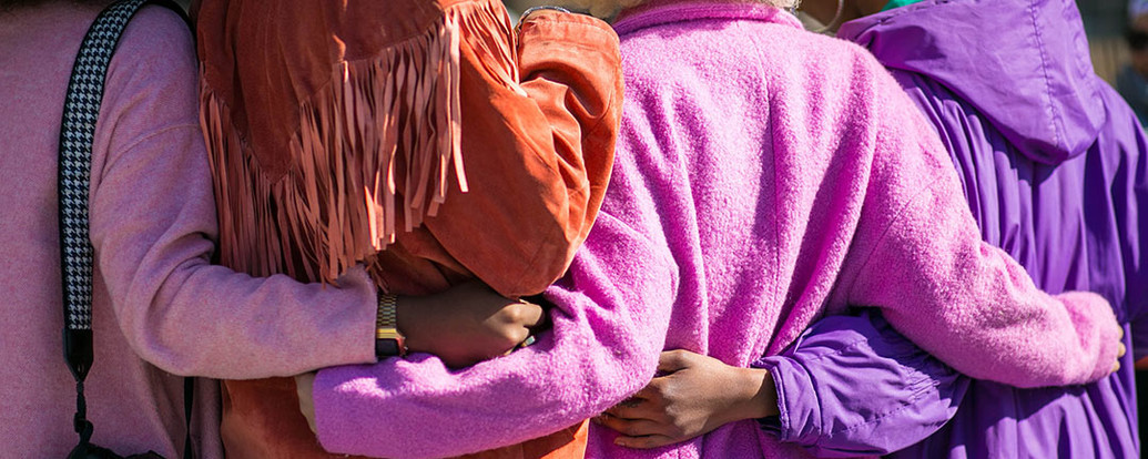 women hugging from the back in purple clothing