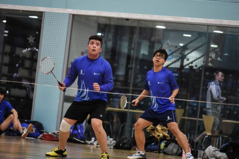 Two badminton players mid-game behind the net.