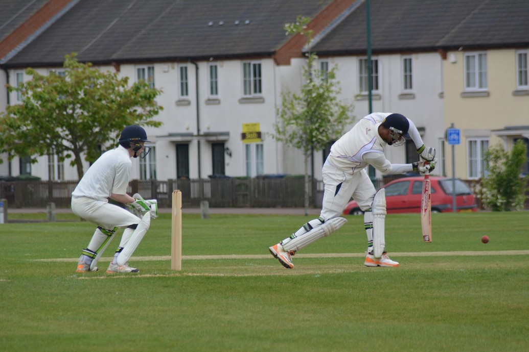 Cricket players. One is in mid swing trying to hit the ball. The other is positioned behind the wicket.