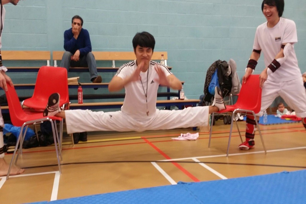 Taekwondo fighter doing the splits on two chairs.