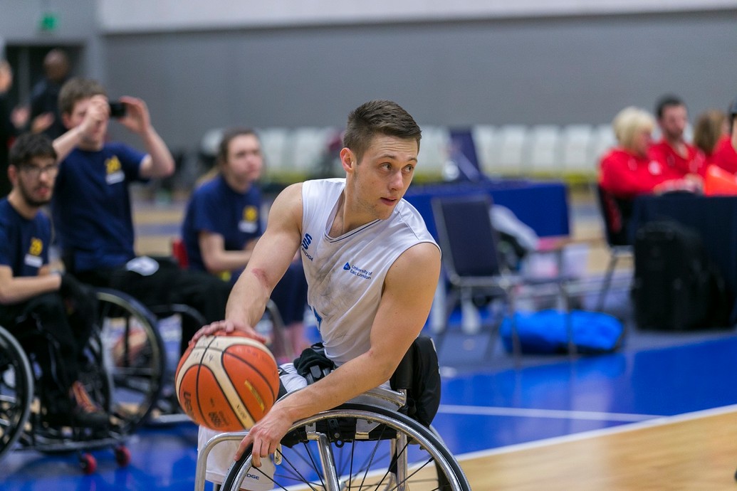 Wheelchair basketball player about to pass the ball.