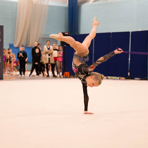 Young gymnast doing a one handed twisted handstand.