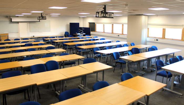 Main conference room with rows of desks and blue chairs.
