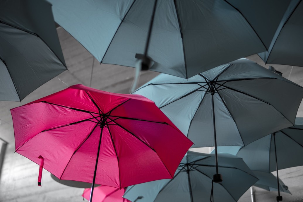 Pink umbrella among other grey ones